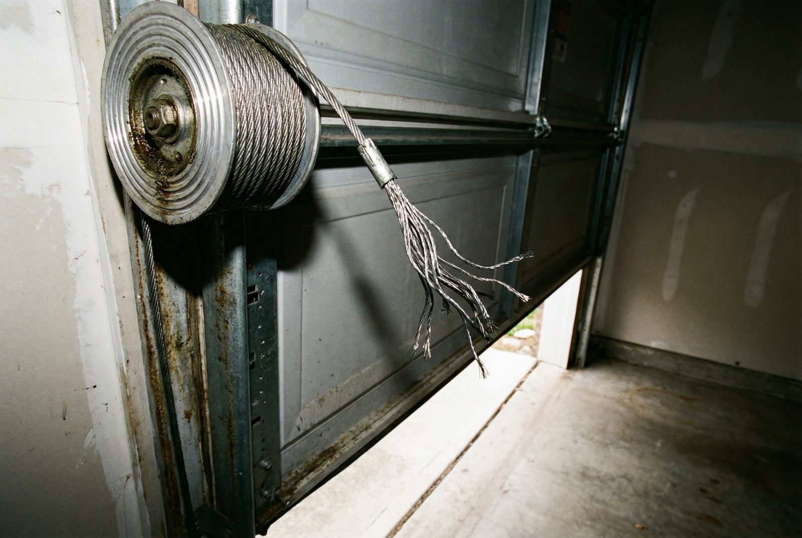 Technician repairing a snapped garage door cable on an emergency call in Gilbert, AZ